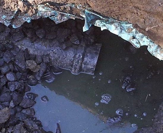 A cracked, corroded sewer line excavated from the ground